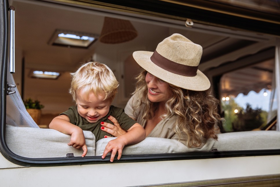 Mum and child in camper van spend time together play laughing.