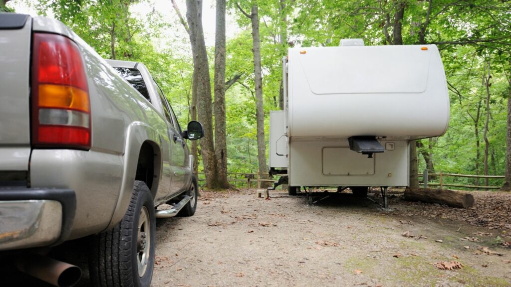 An unhitched fifth wheel parked at a campsite next to a towing truck
