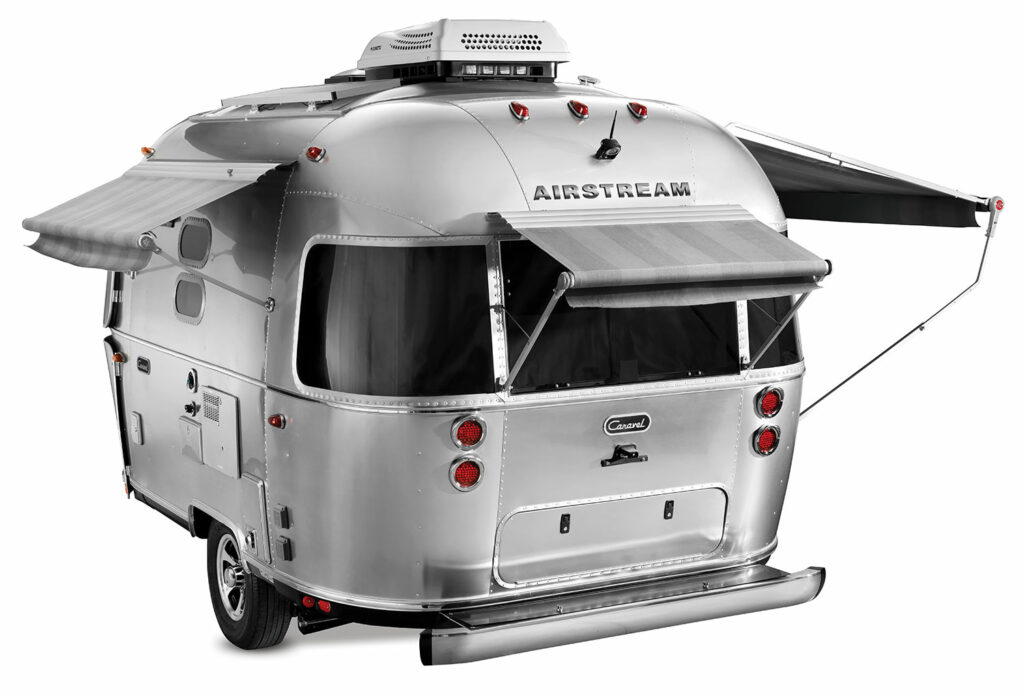 Rear view of the exterior of the Airstream Caravel isolated on a white background with two awnings extended.