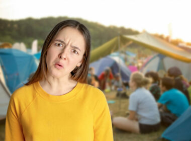 A portrait of a confused girl with campers and tents in the background.