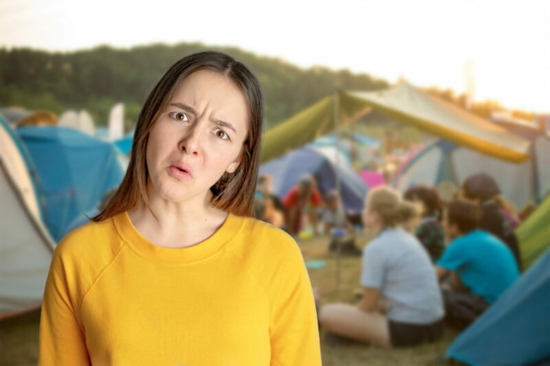 A portrait of a confused girl with campers and tents in the background.