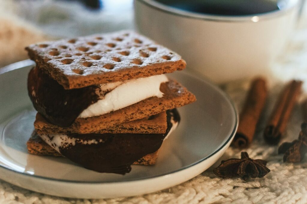 Homemade s'mores on a dish next to a hot mug of a coffee.