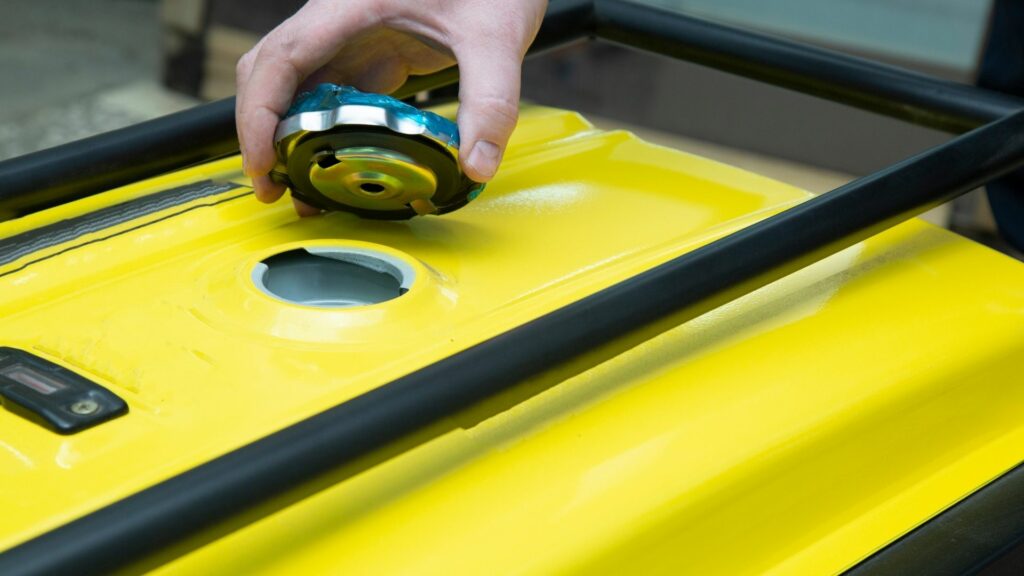 Opening up the fuel cap on the top of a portable generator.