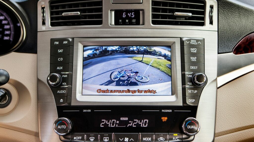 The monitor of a rear view backup camera displays a tipped over bike behind the vehicle