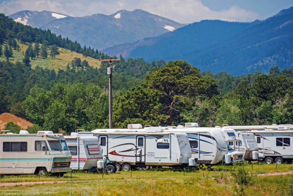 A busy RV park in the mountains with several trailers lined up.