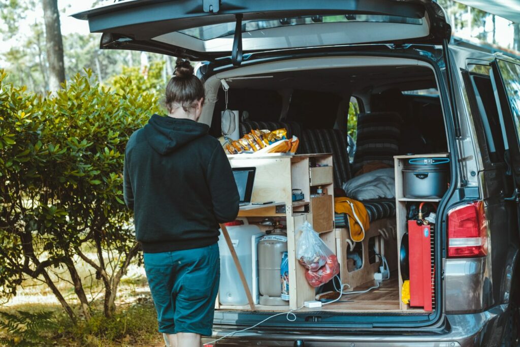 A person uses a laptop that is plugged into his camper van.