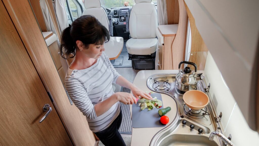 A woman cuts vegetables in her RV where counter space is very limited.