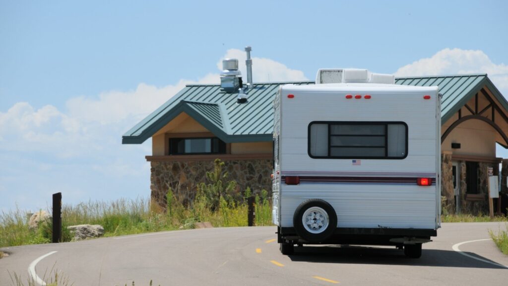 An RV pulls into the driveway of a campground and stops at the office building to check in.