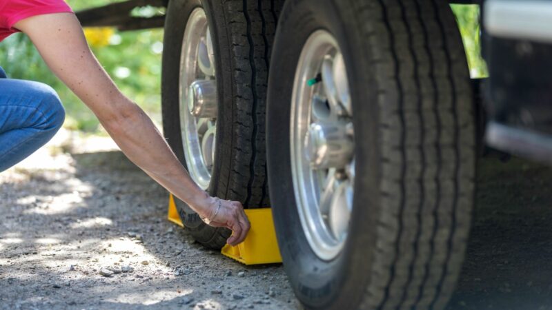 A woman adds tire blocks around the back of her travel trailer.