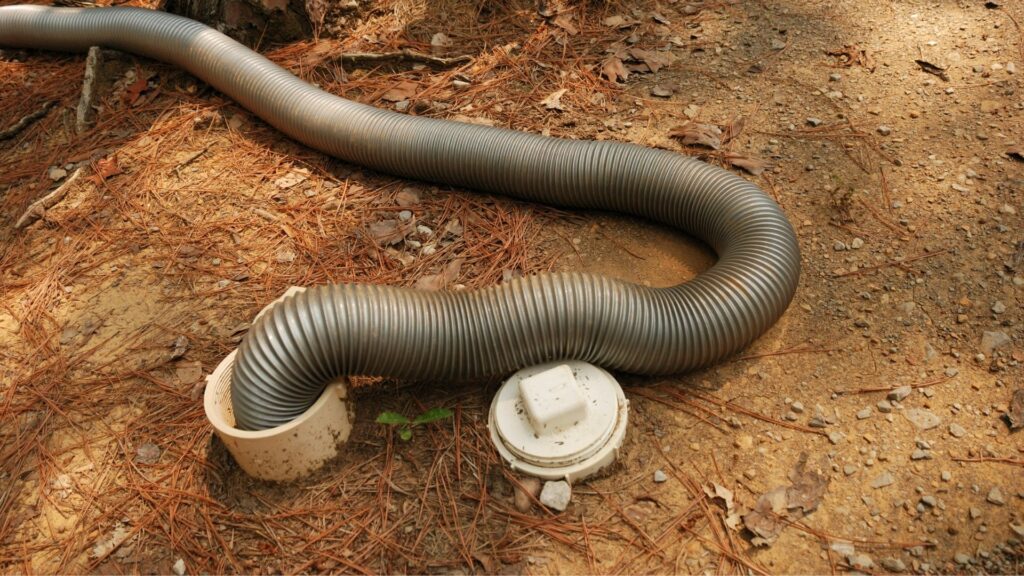 A black sewage hose connected to a ground sewage cap.