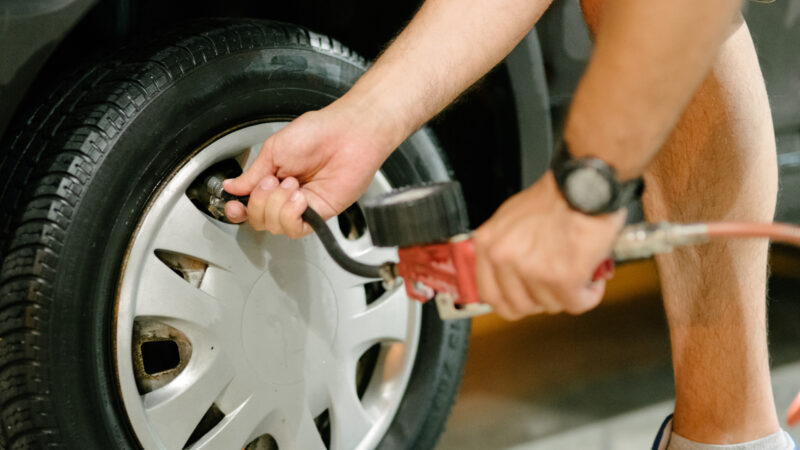 A hand fills a tire with an air compressor.