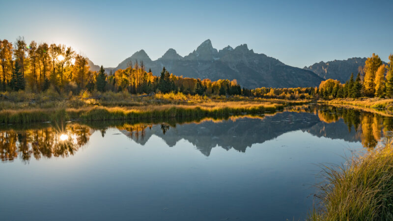 The teton mountains reflect on a river in the Bridger Teton National Forest.