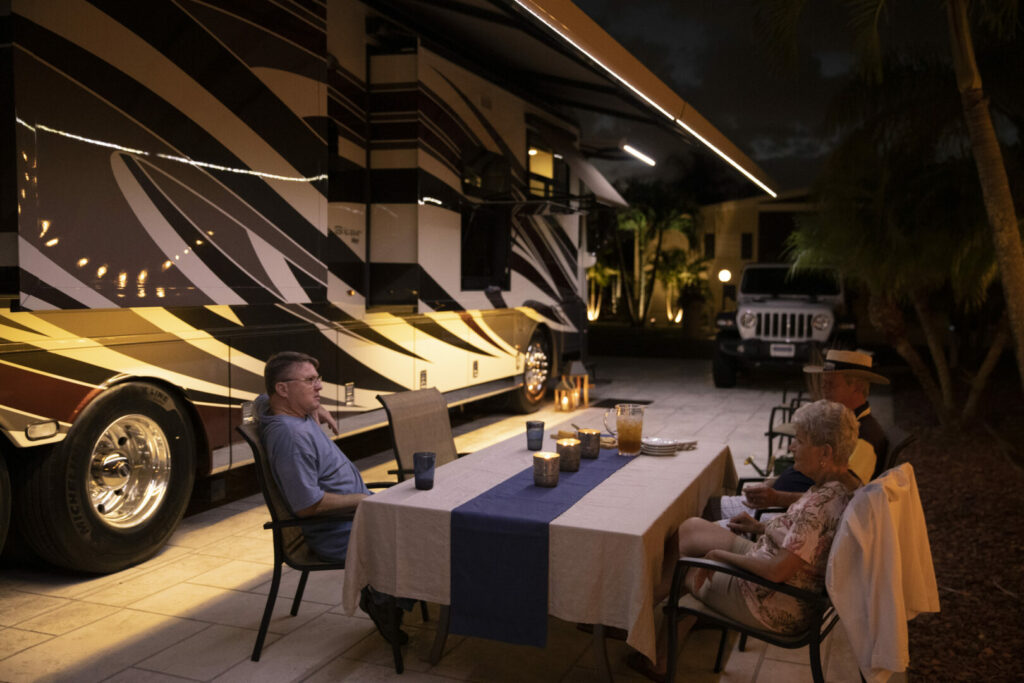 A couple sits outside enjoying dinner next to their luxury Newmar RV