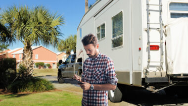 A man holds a clipboard in front of his RV as he works his way through his RV checklist.