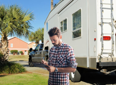 A man holds a clipboard in front of his RV as he works his way through his RV checklist.