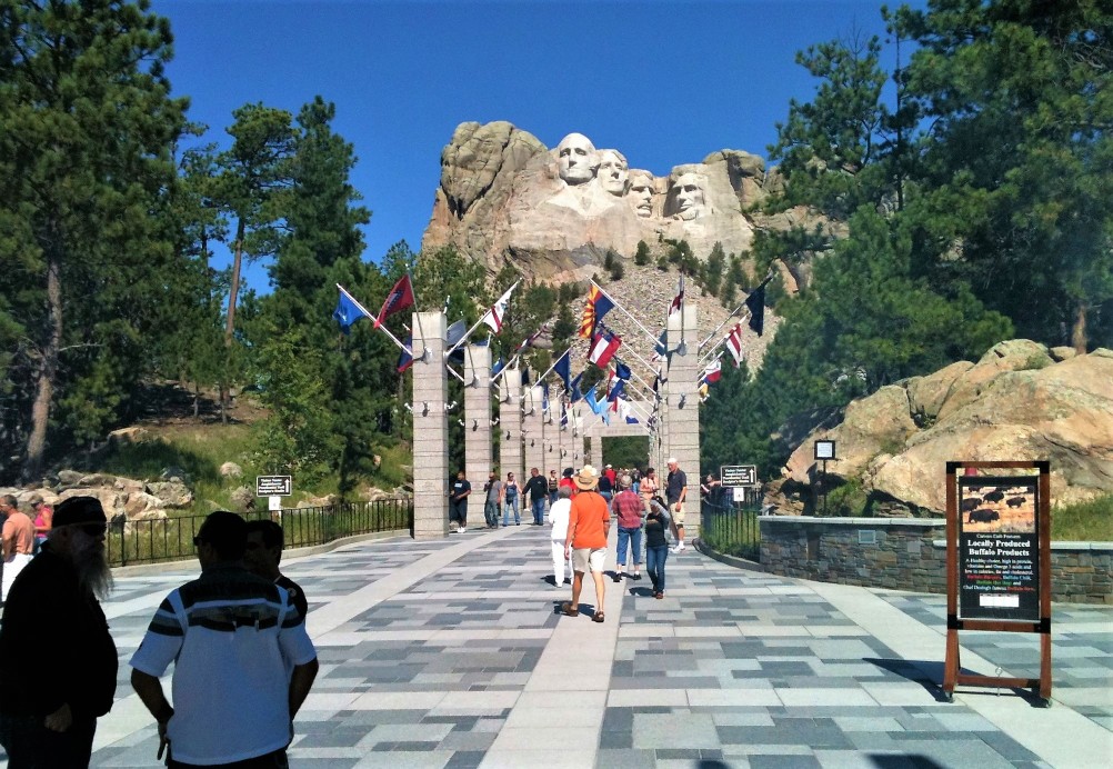 Walking up to Mount Rushmore in South Dakota along a polished sidewalk lined with flags.