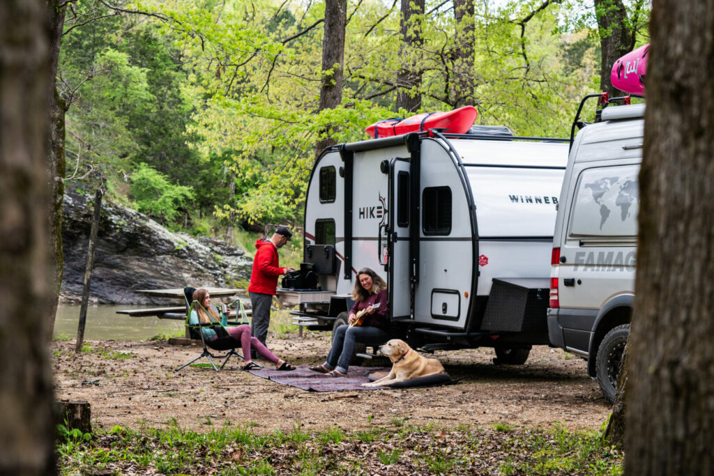 A family and their dog enjoys the outdoors besides their reliable Winnebago travel trailer.