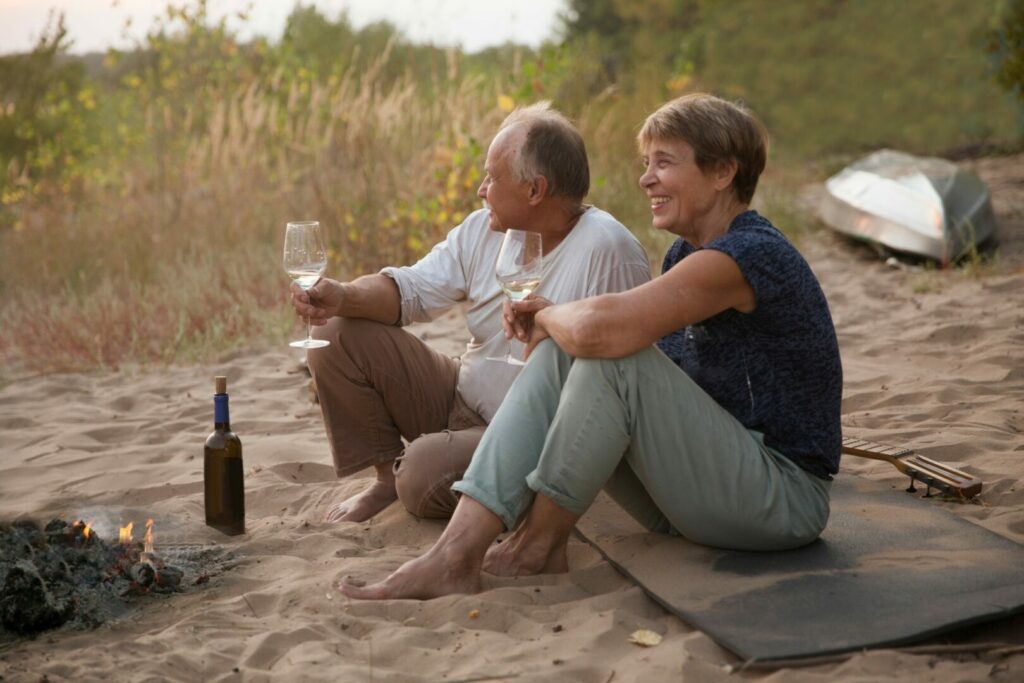 Couple sitting on beach together drinking wine