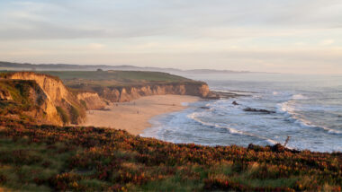 Half Moon Bay coast line and cliff shine in the golden light of the sunset.