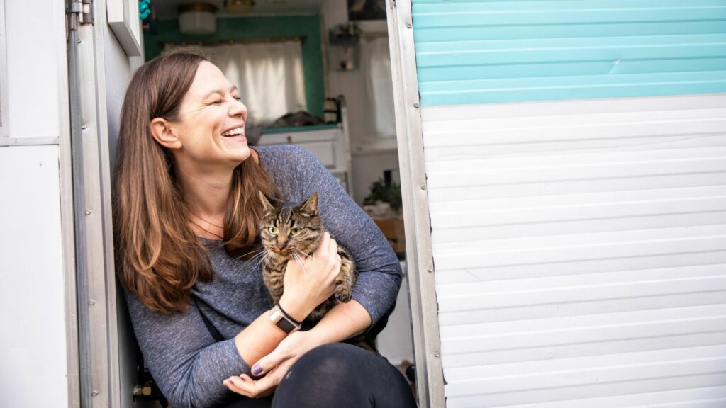 Woman holding her cat as she sits in the doorway in an RV.