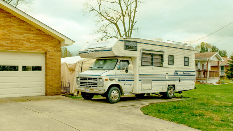 Motorhome parked on a camper pad in a driveway.