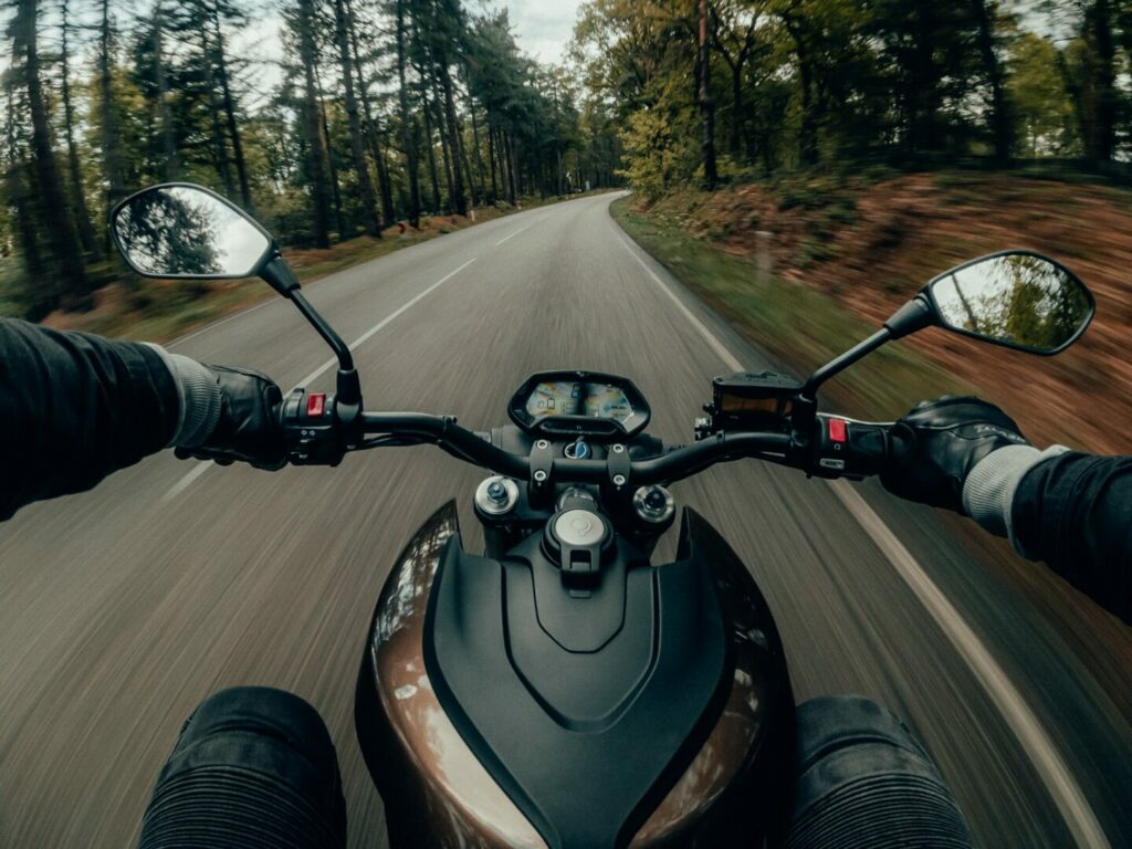 Driver's view of a motorcycle speeding down a forested road.