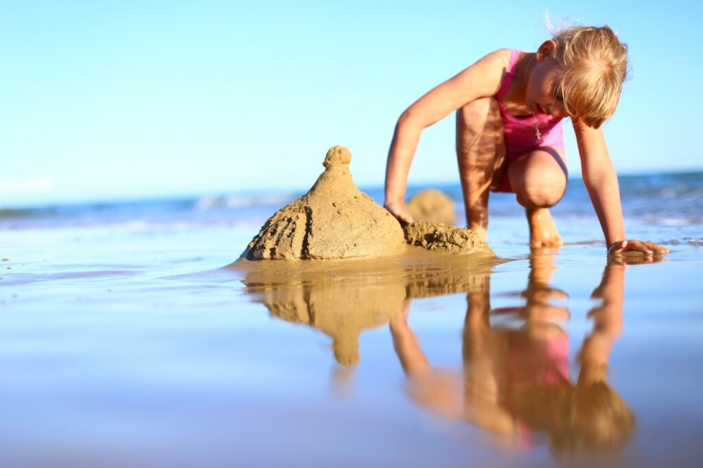 A young child making sand castles on the beach.