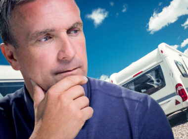 A man ponders who makes Keystone RVs with travel trailers in the background