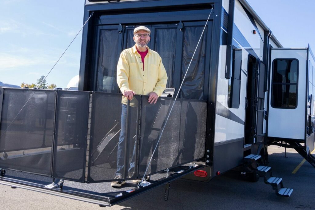 A man stands on the balcony created by his RV toy hauler.