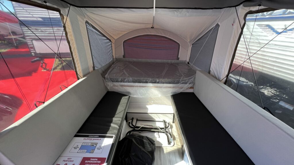 The inside of a pop up camper with a bed and two benches 