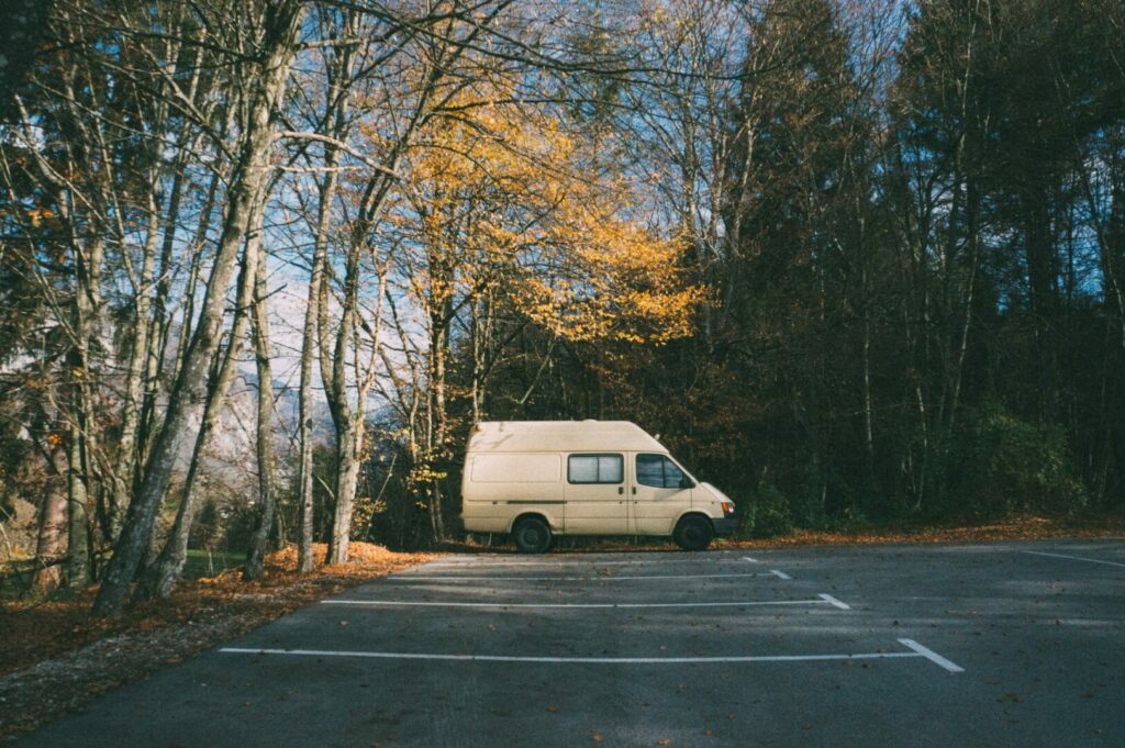 A white van has window coverings for privacy and to avoid drawing attentions while stealth camping in a park.