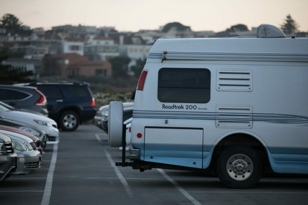 A camper van in a parking lot with other vehicles.