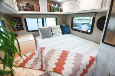 A modern camper decorated with cute blankets, plants, and pillows.