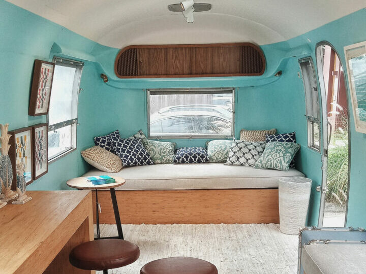 The interior of a remodeled RV with modern decor and bright teal walls.