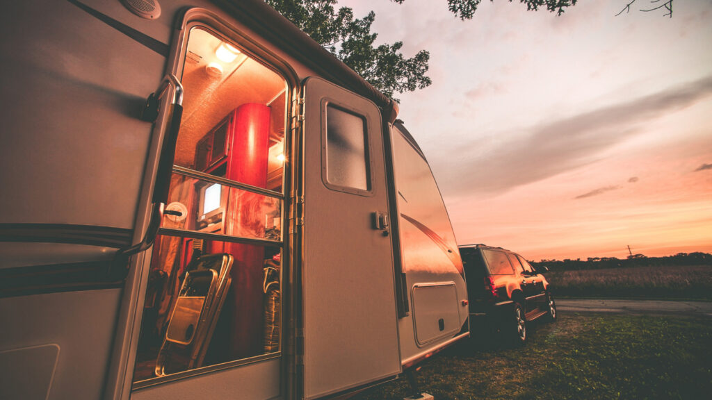 A travel trailer is lit up in the sunset light and full of all the accessories needed for a fun and easy camping trip.