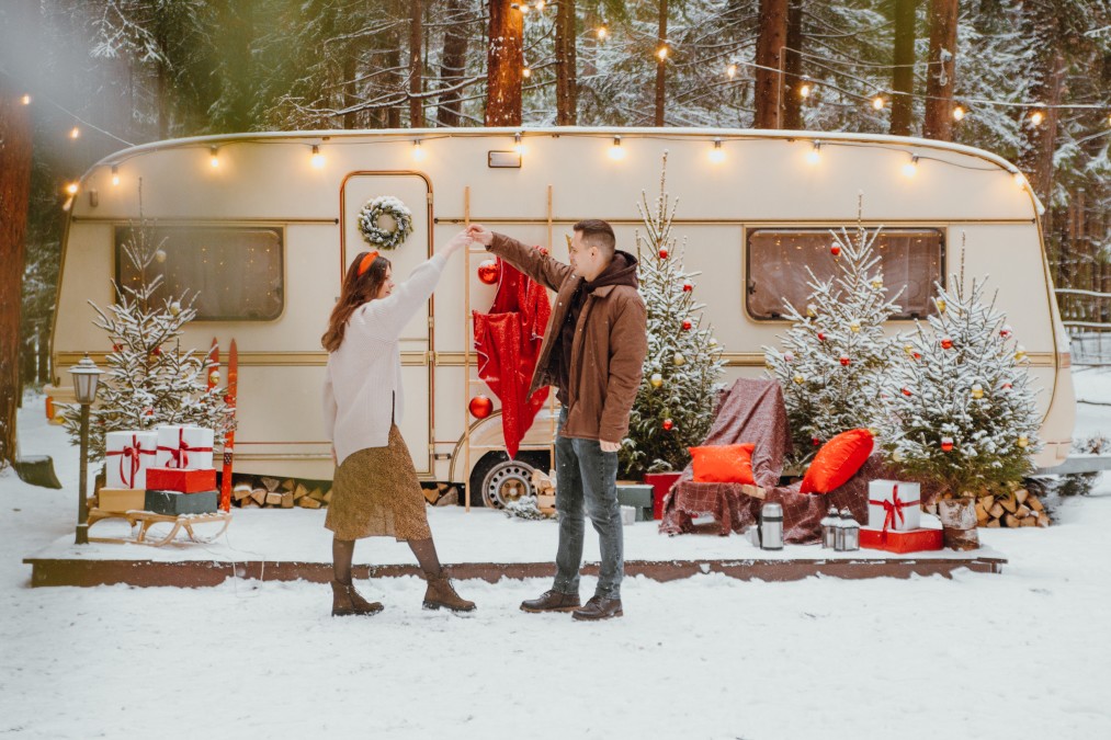A couple dances outside of their home, a travel trailer, in the winter.