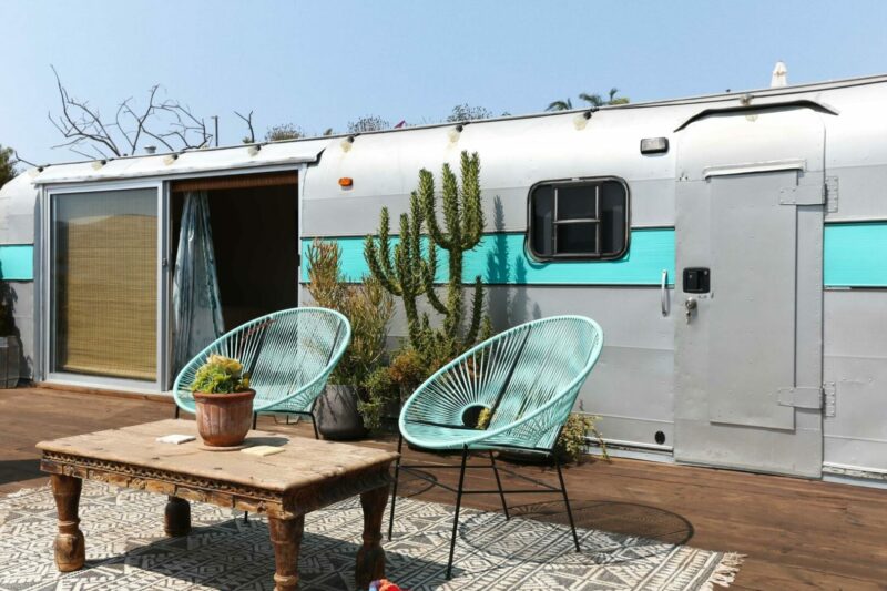 A stationary RV in the desert has been customized with a sliding glass patio door and a large deck.