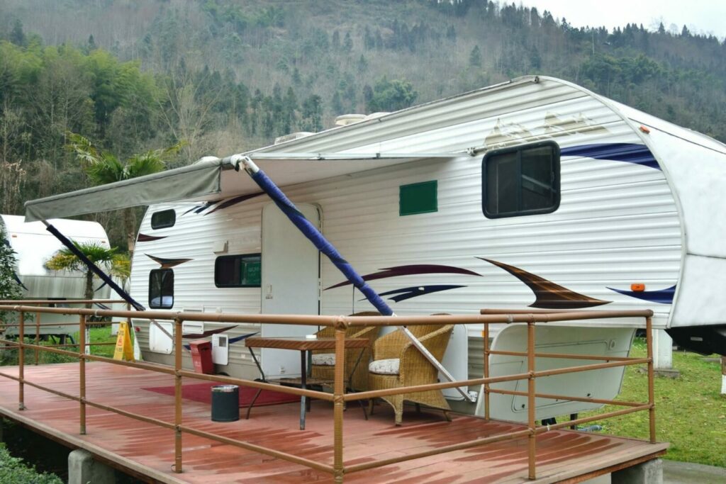 A fifth wheel parked next to a raised deck for stationary RV living.