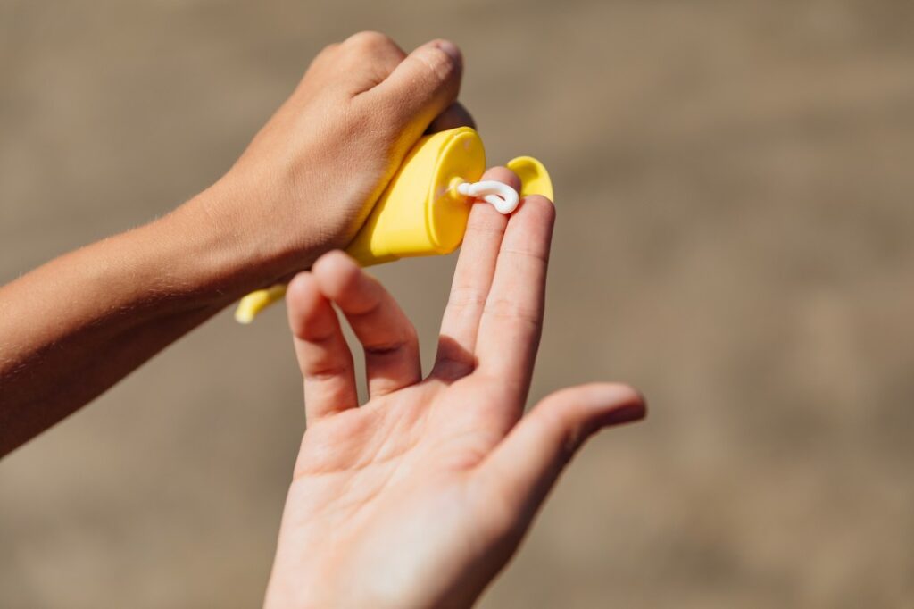 Close up of hands squeezing a tube of sun screen getting ready to protect their skin at a nudist RV park 