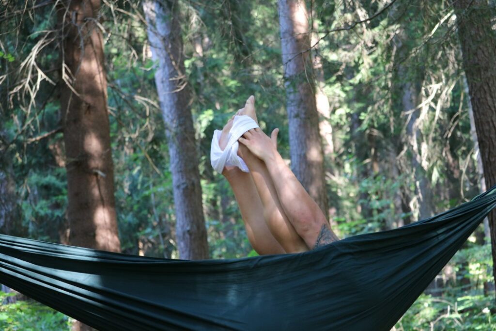 A person struggles to take off their underwear in a hammock.