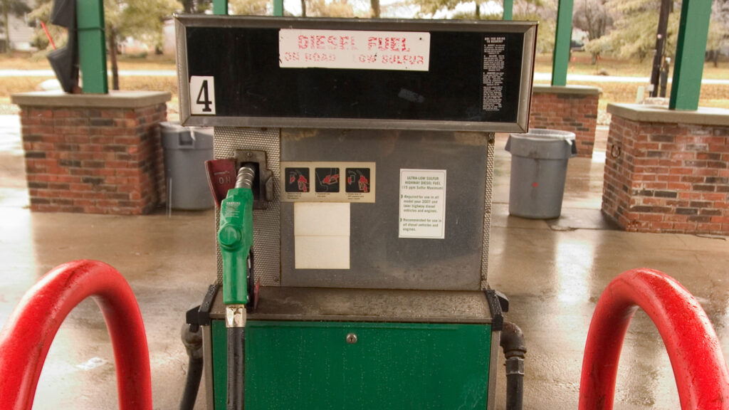 A diesel fuel pump looks worn down and old at an empty gas station.