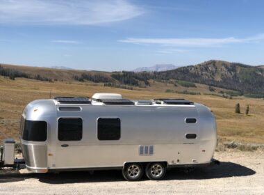 An airstream parked in the desert with solar panels on the roof.