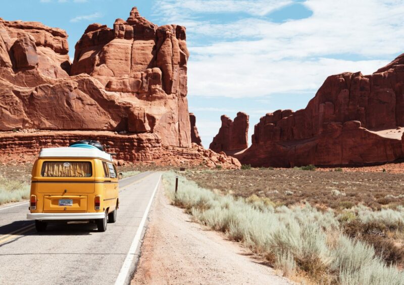 Retro van driving into Arches National Park in Moab, Utah, on a road trip cross country.