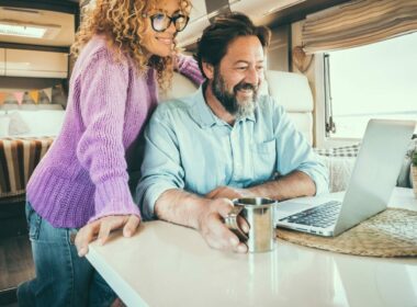 A couple looks at their laptop together while sitting at an RV dinette