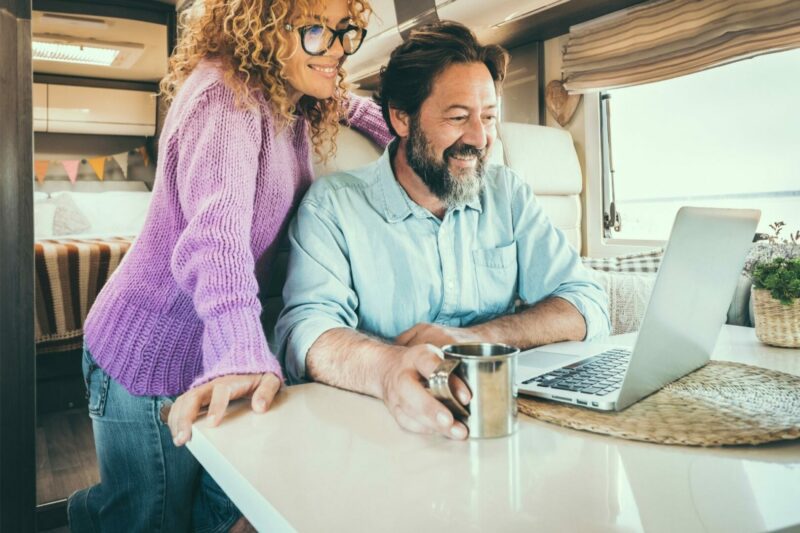 A couple looks at their laptop together while sitting at an RV dinette