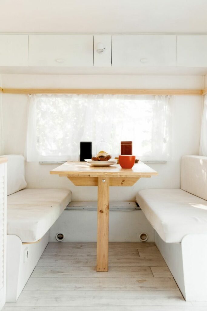 RV dining table with to benches with white cushions.