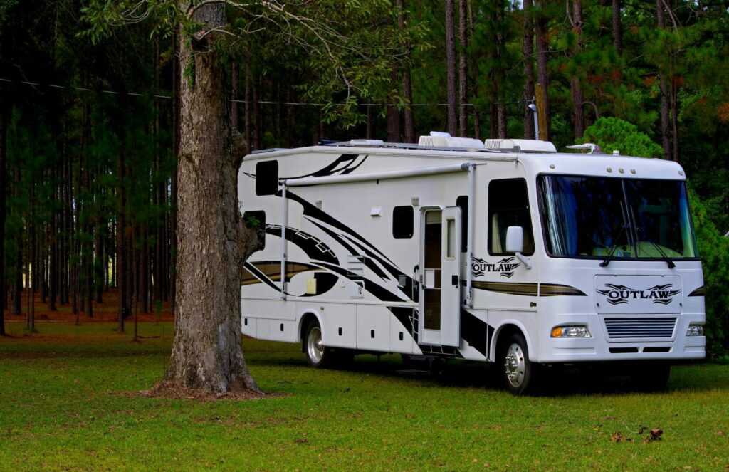 The Outlaw, a class A motorhome, parked in a forested campground.