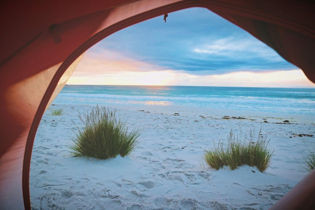 View from inside of a tent looking out along the oceanfront while spending the night beach camping.