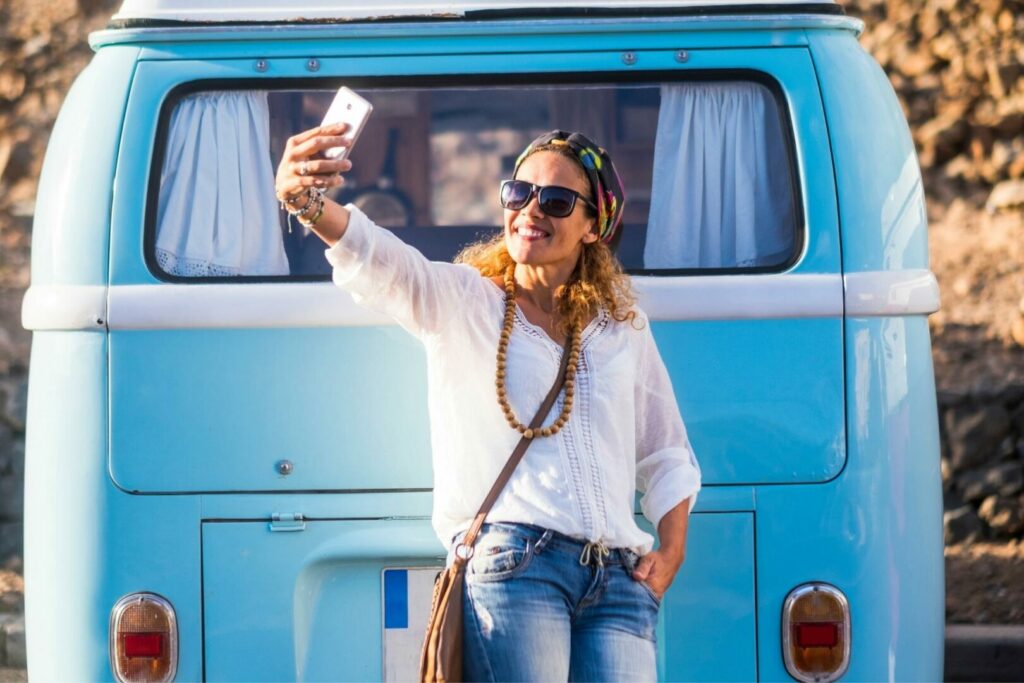A woman takes a selfie near her campervan.