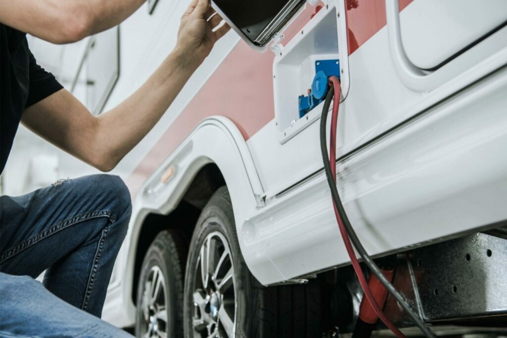 A person inspects their RV electrical power supply connection.